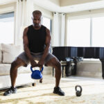 African-American man exercising at home with kettlebells